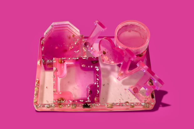 Pink and clear plastic trey set with real sea shells and glass on a pink background