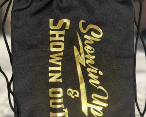 A black carrying bag with the text 'SHOWIN UP & SHOWIN OUT' printed in gold.