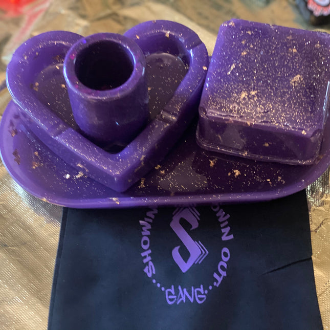 A purple soap dish shaped like a heart, with a candle next to it, adding charm to a bathroom decor.