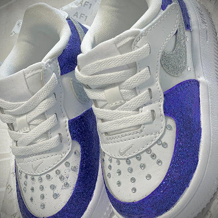 White sneakers with Royal Purple Color accents and rhinestone details on a light gray background