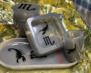Customized grey trey set with a canister and ashtray featuring black scorpio designs on them, displayed on a yellow surface.